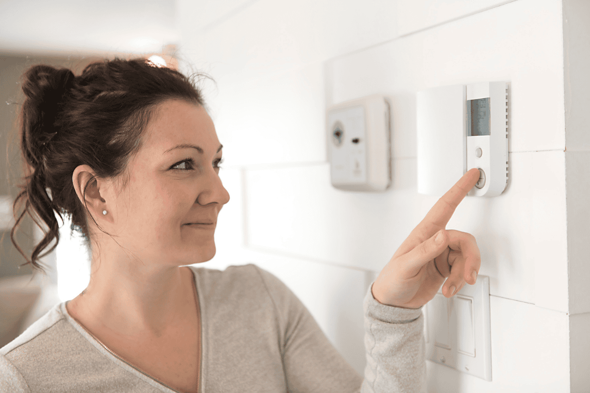 A lady changing the thermostat